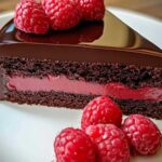 Eindresultaat van de afgewerkte chocolade-frambozen truffeltaart versierd met verse frambozen