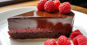 Doorsnede van een chocolade-frambozen truffeltaart met zichtbare laagjes en glanzende ganache