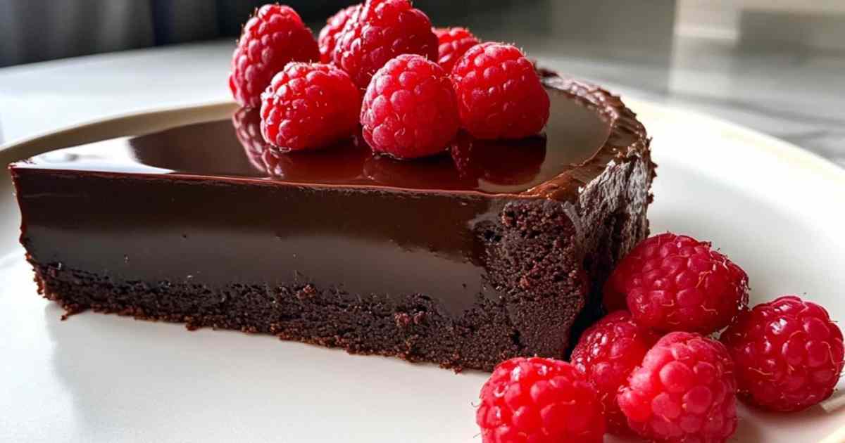 Doorsnede van een chocolade-frambozen truffeltaart met zichtbare laagjes en glanzende ganache