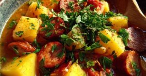 Zutaten für Kartoffelgulasch ausgelegt auf Holzschneidebrett