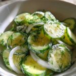 Ingrediënten voor de klassieke komkommersalade: komkommers, een ui, yoghurt, en een flesje azijn.