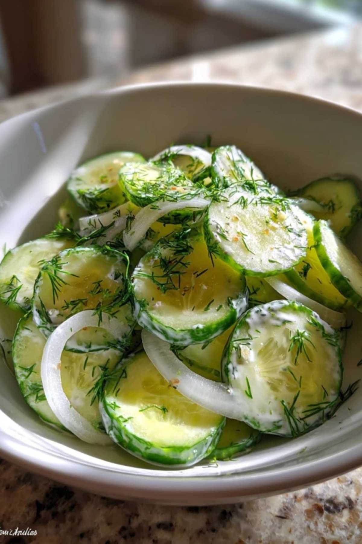 Ingrediënten voor de klassieke komkommersalade: komkommers, een ui, yoghurt, en een flesje azijn.
