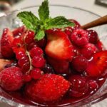 Eine Draufsicht der Zutaten für Rote Grütze: frische Erdbeeren, Himbeeren, rote Johannisbeeren, Zucker und Speisestärke.