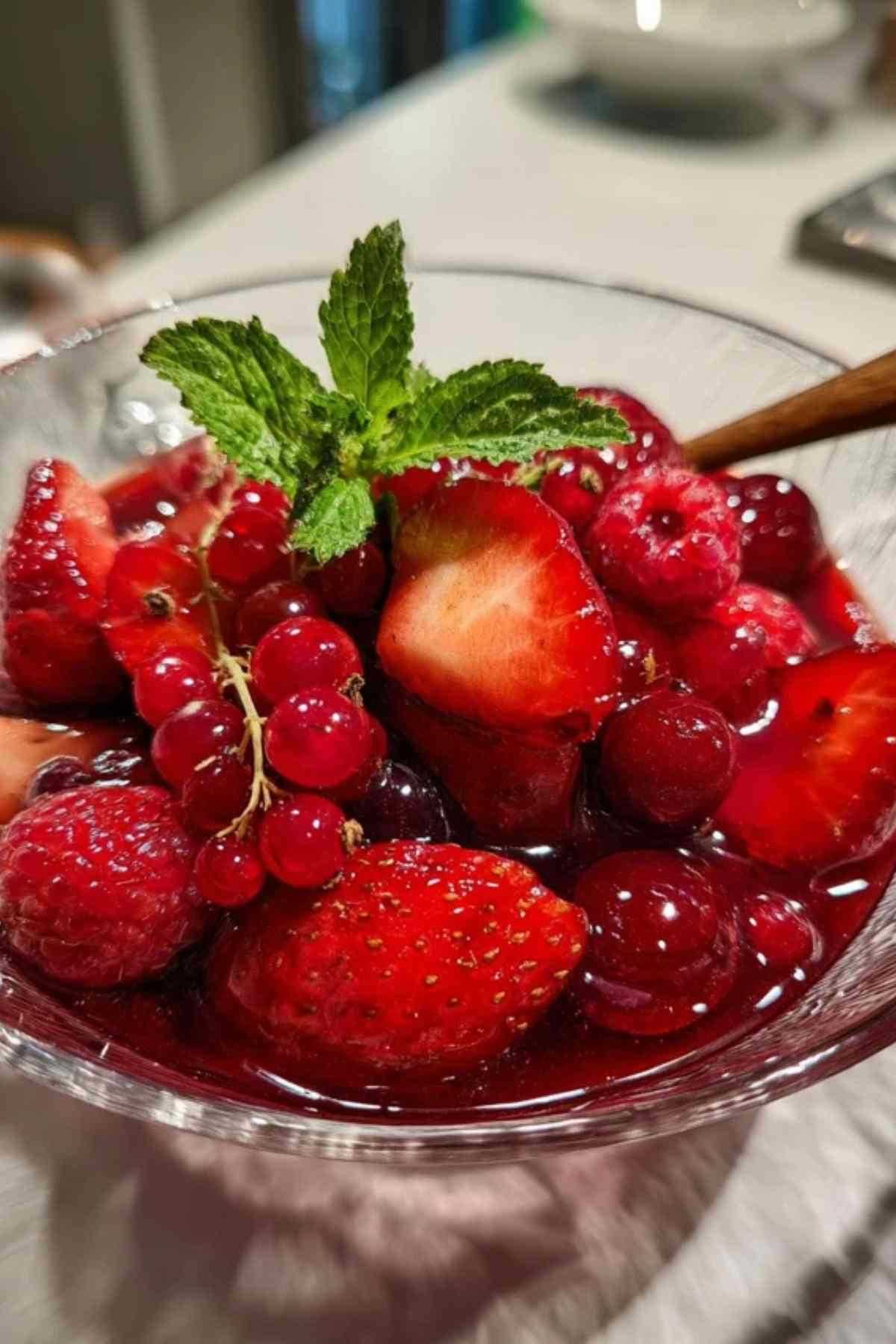 Eine Draufsicht der Zutaten für Rote Grütze: frische Erdbeeren, Himbeeren, rote Johannisbeeren, Zucker und Speisestärke.