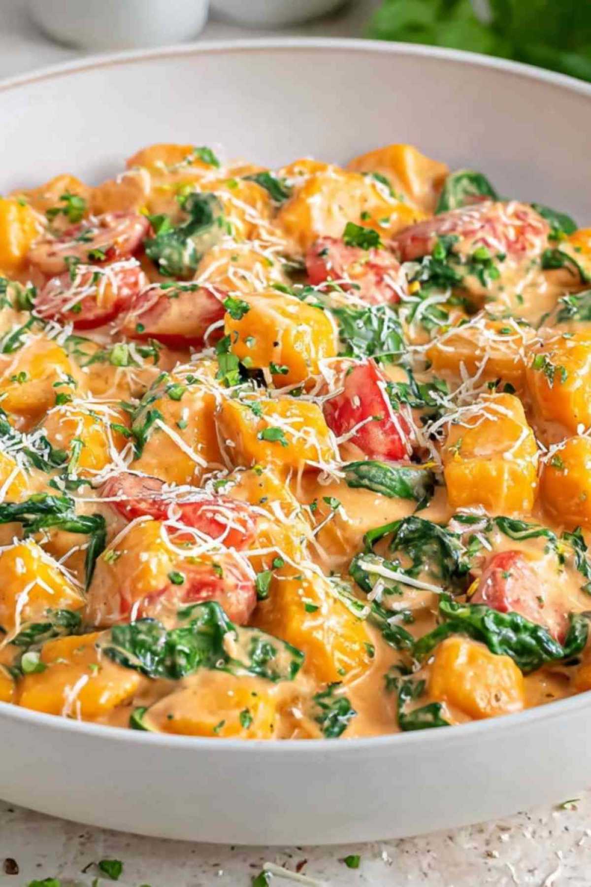 Gnocchi-Pfanne mit Spinat und Tomaten in cremiger Sahnesauce in schwarzer Pfanne