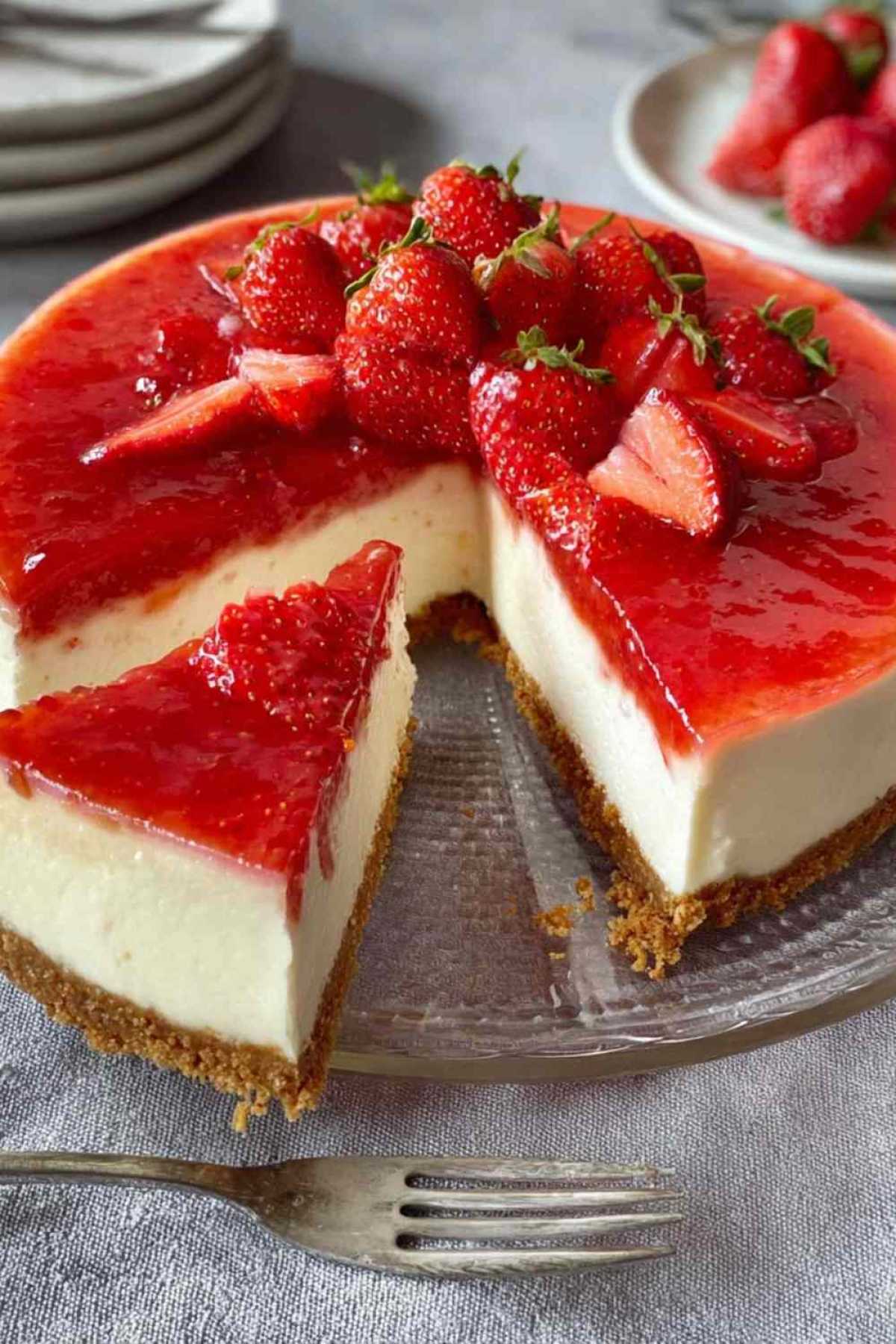 Erdbeer Cheesecake mit marmorierter Erdbeerfüllung auf weißer Kuchenplatte serviert