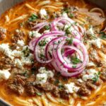 Kritharaki-Hackfleischpfanne mit Feta servierfertig in schwarzer Pfanne mit zerbrösteltem Feta
