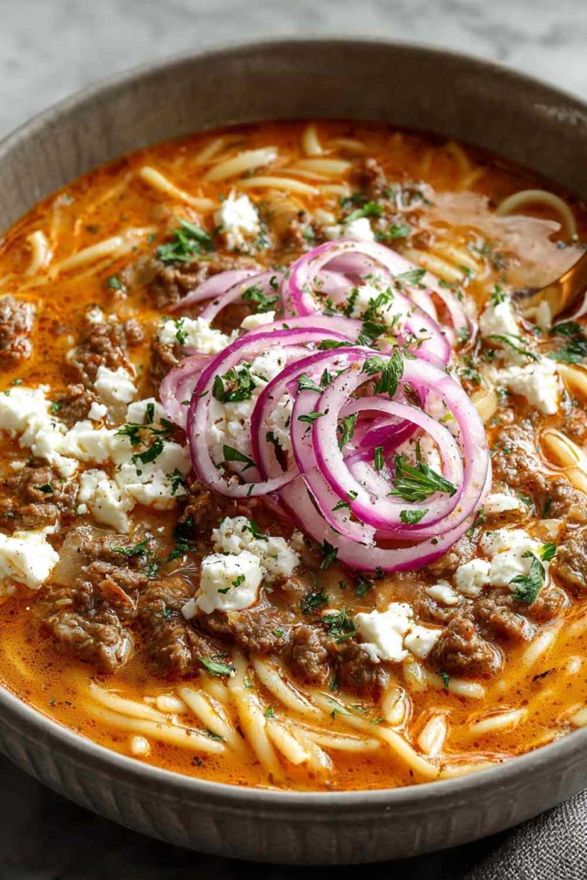 Kritharaki-Hackfleischpfanne mit Feta servierfertig in schwarzer Pfanne mit zerbrösteltem Feta