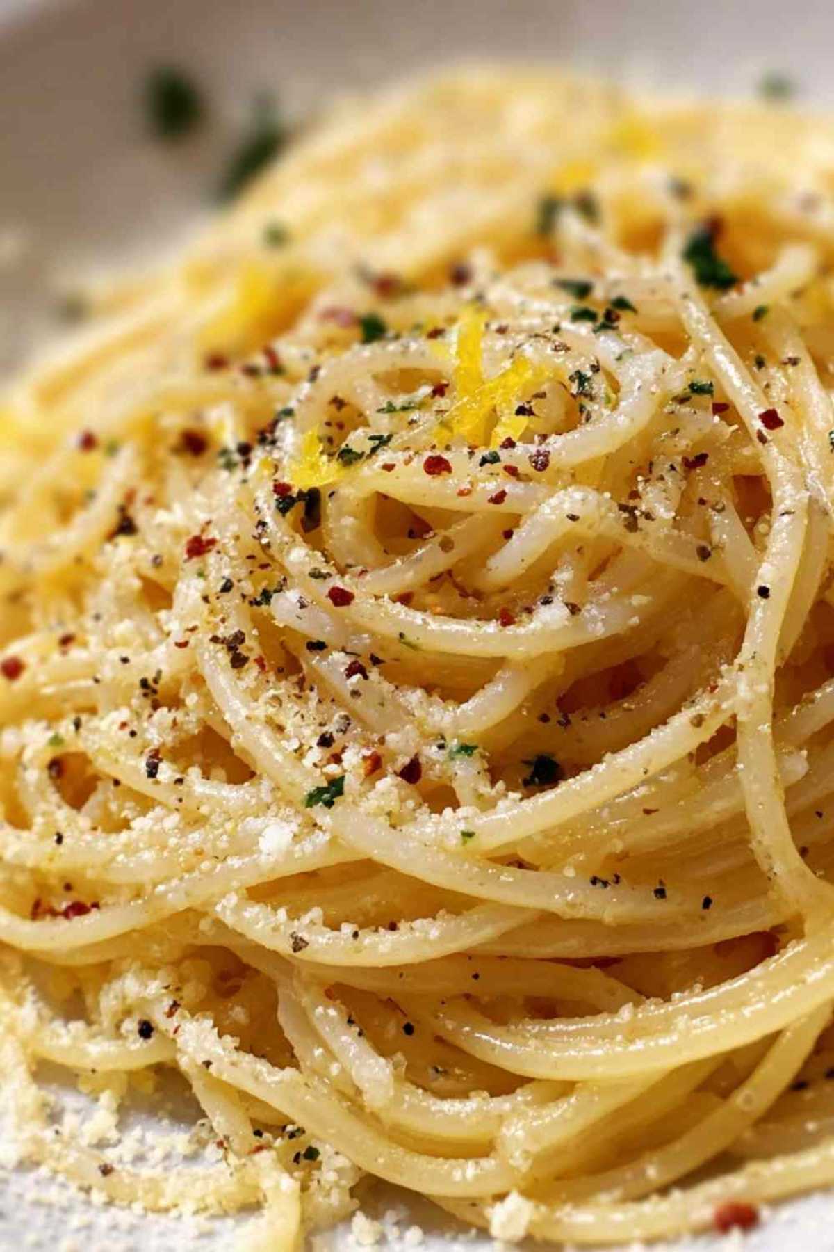 Midnight Pasta mit Knoblauch, Olivenöl und frischer Petersilie serviert auf weißem Teller