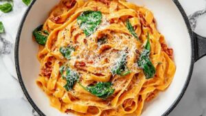 Vegane cremige getrocknete Tomaten Pasta in schwarzer Pfanne mit frischen Kräutern