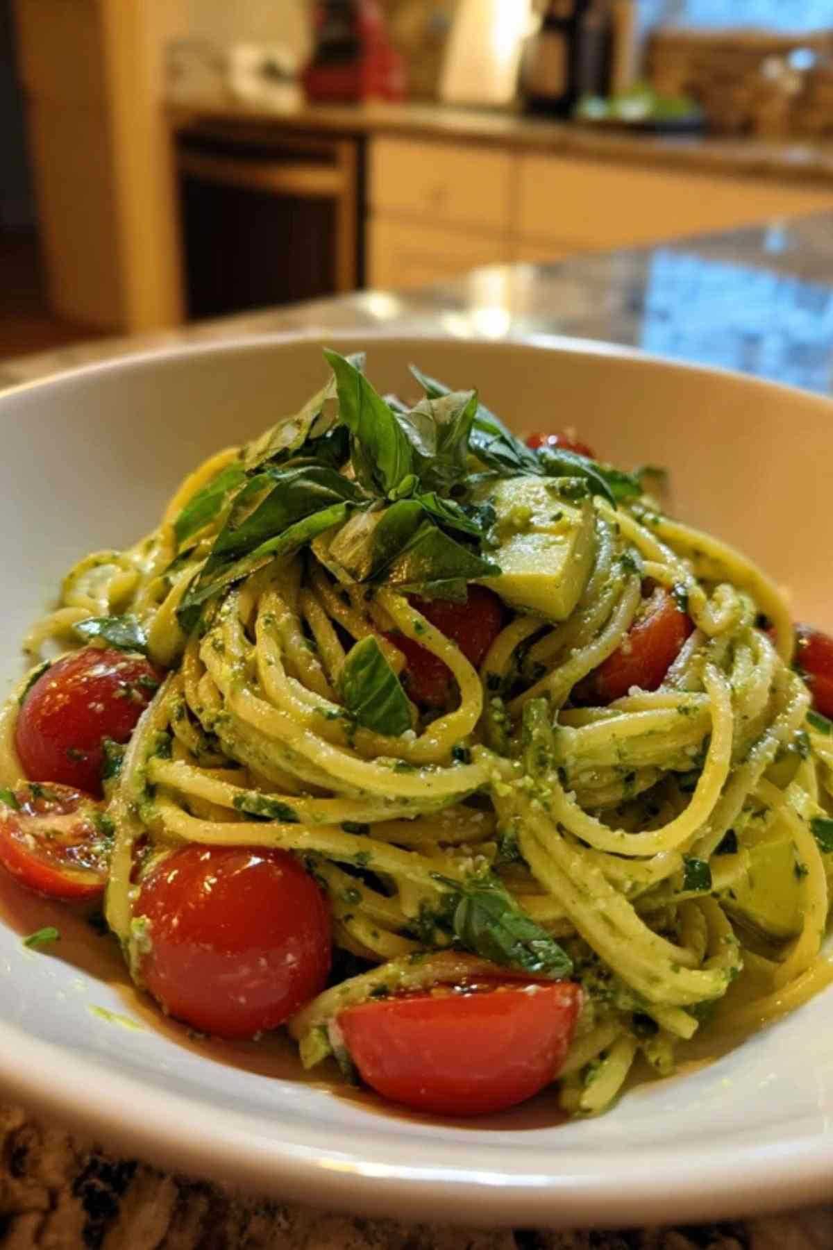 Cremige Avocado Pasta in weißer Schüssel mit Basilikum garniert