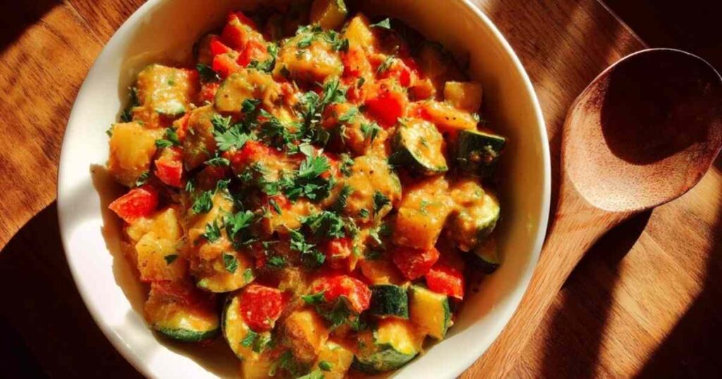 Zutaten für Zucchini-Pfanne aufgereiht auf Holzbrett