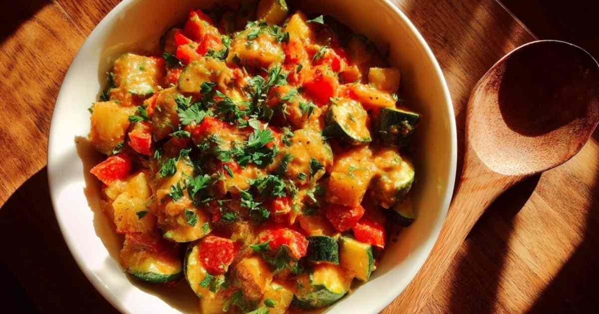 Zutaten für Zucchini-Pfanne aufgereiht auf Holzbrett