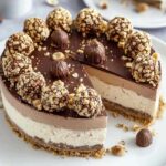 Ferrero Rocher Torte ohne Backen auf weißem Kuchenteller mit goldenen Pralinen dekoriert