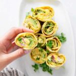Kichererbsen-Salat-Röllchen aufgeschnitten auf Holzbrett zeigen cremige Füllung mit Spinat