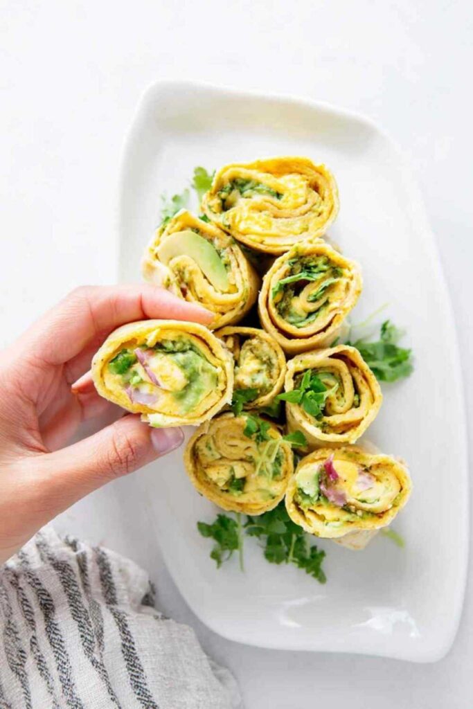 Kichererbsen-Salat-Röllchen aufgeschnitten auf Holzbrett zeigen cremige Füllung mit Spinat
