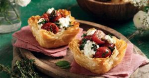 Mediterrane Blätterteigtartelettes mit Zucchini und Tomaten goldbraun gebacken auf Backblech