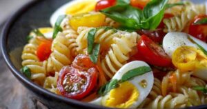 Caprese Pasta Salat mit Kirschtomaten, Mozzarella und Basilikum in weißer Schüssel