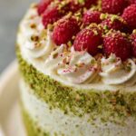 Pistazien-Himbeer-Torte mit Mascarpone-Creme elegant dekoriert auf weißer Tortenplatte
