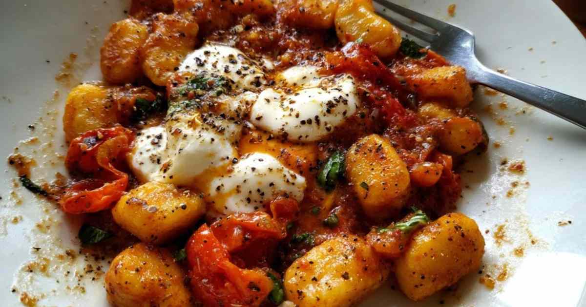 Close-up von Gnocchi mit Tomaten und zerlaufendem Mozzarella auf Gabel