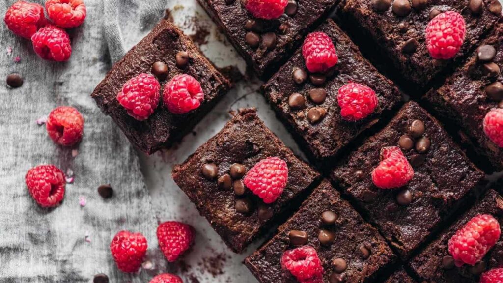 Frisch gebackene vegane Himbeer-Brownies auf Kühlgitter mit sichtbaren Himbeeren
