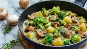 Brokkoli-Kartoffel-Pfanne mit Pilzen in schwarzer Pfanne mit frischer Petersilie garniert