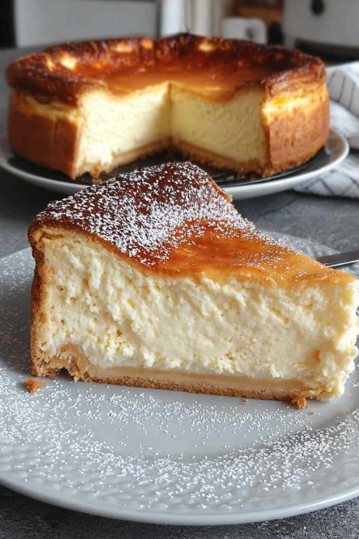 Der cremigste Käsekuchen aller Zeiten auf weißer Tortenplatte mit goldbrauner Oberfläche