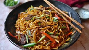 Gebratene Asia Nudeln mit buntem Gemüse in der Pfanne beim Braten