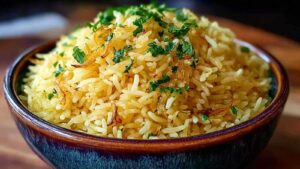 Goldener Zwiebel Butter Reis in großer Pfanne mit karamellisierten Zwiebeln und dampfendem Reis