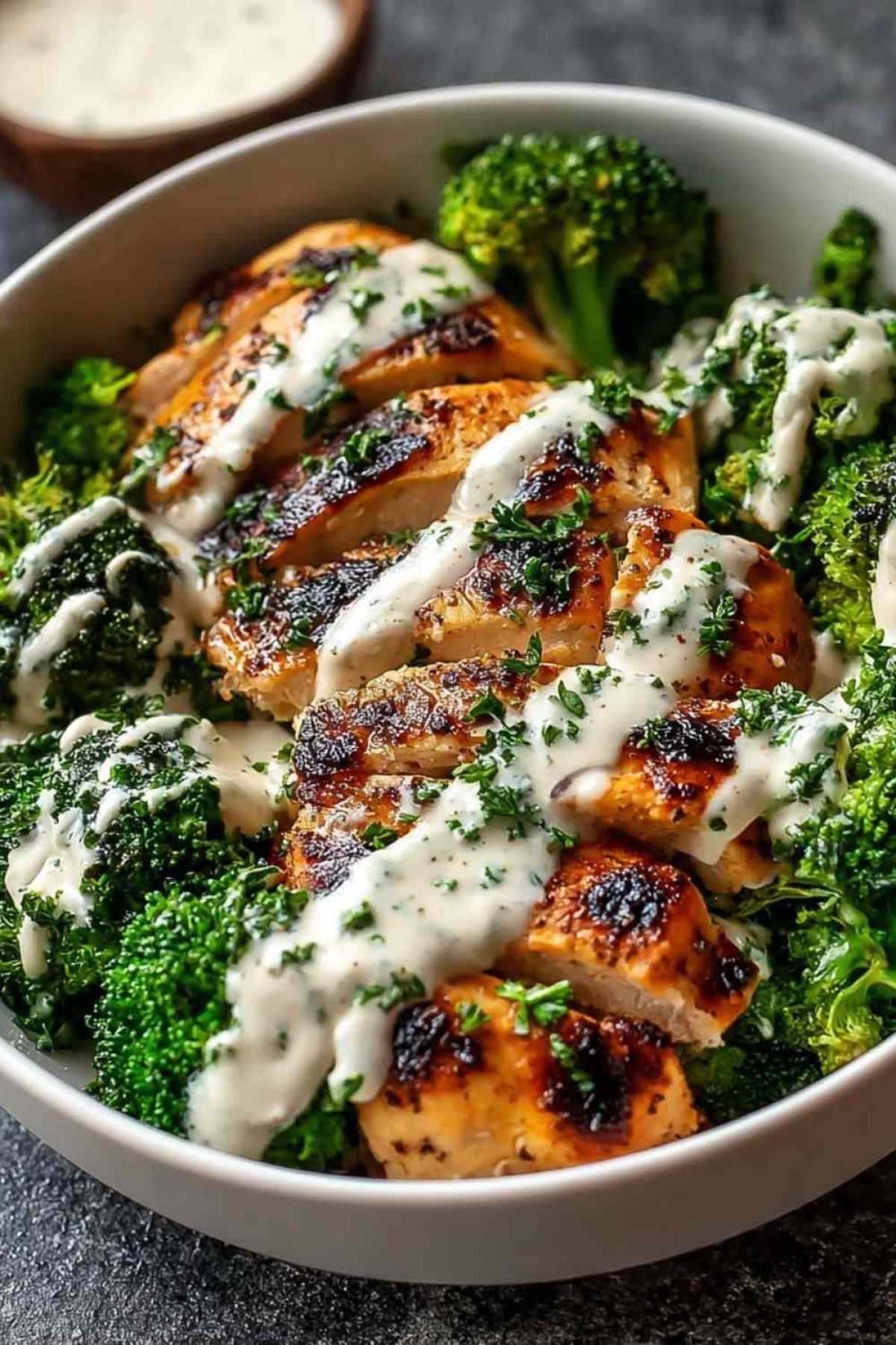 Gegrilltes Hähnchen mit Brokkoli und cremiger Knoblauch-Sahne-Sauce in einer Bowl angerichtet