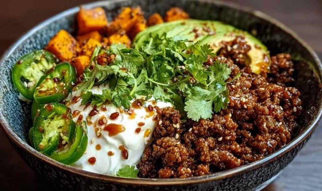 Hackfleisch Hot Honey Bowl mit gerösteten Süßkartoffeln Avocado und Hüttenkäse auf weißem Teller