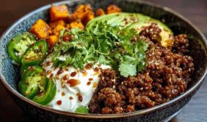 Hackfleisch Hot Honey Bowl mit gerösteten Süßkartoffeln Avocado und Hüttenkäse auf weißem Teller