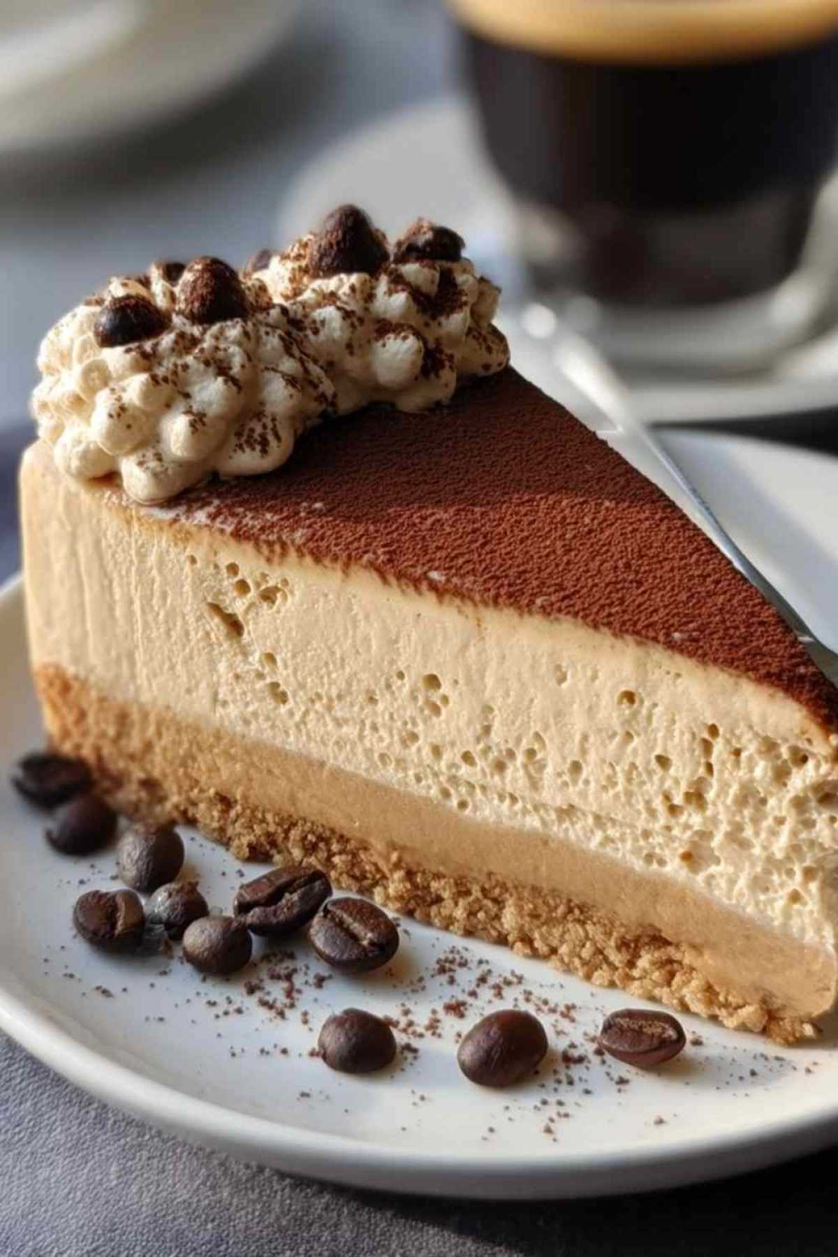 Espresso-Mascarpone-Käsekuchen mit Kakaopulver bestäubt auf weißem Teller
