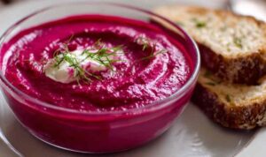Rote-Bete-Aufstrich mit Meerrettich in weißer Schüssel mit frischen Kräutern garniert