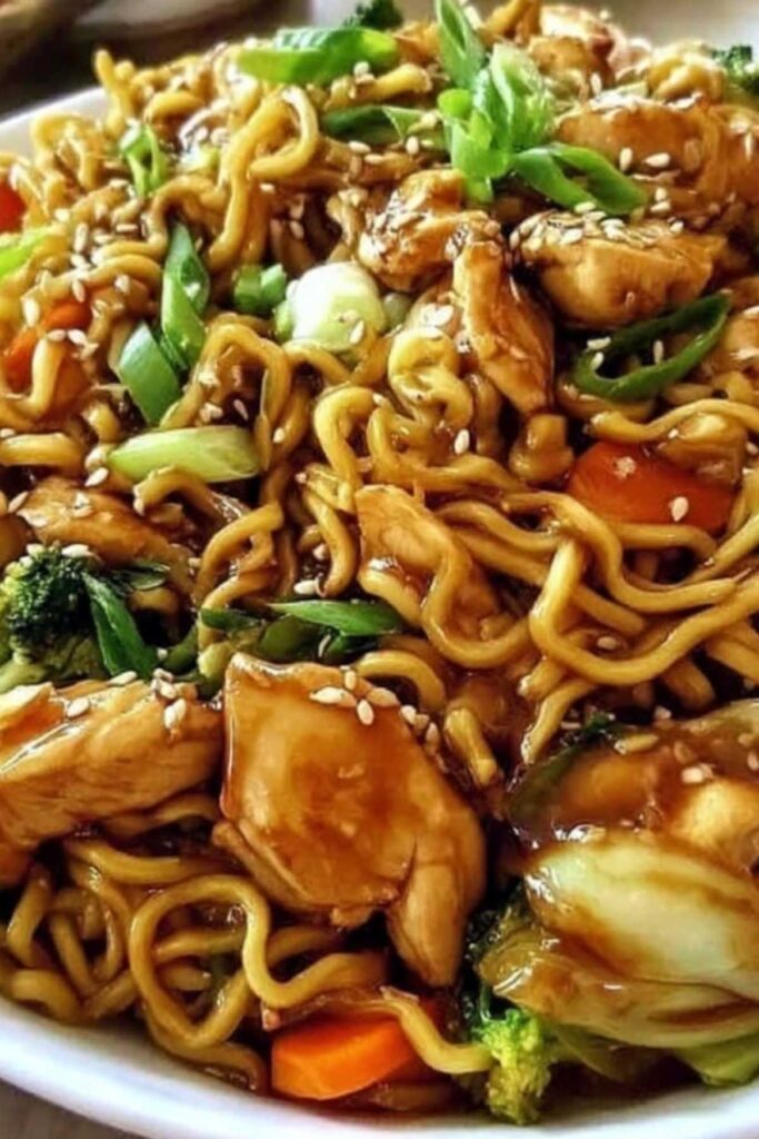 Portion chinesische gebratene Nudeln mit Hähnchen auf weißem Teller servierfertig