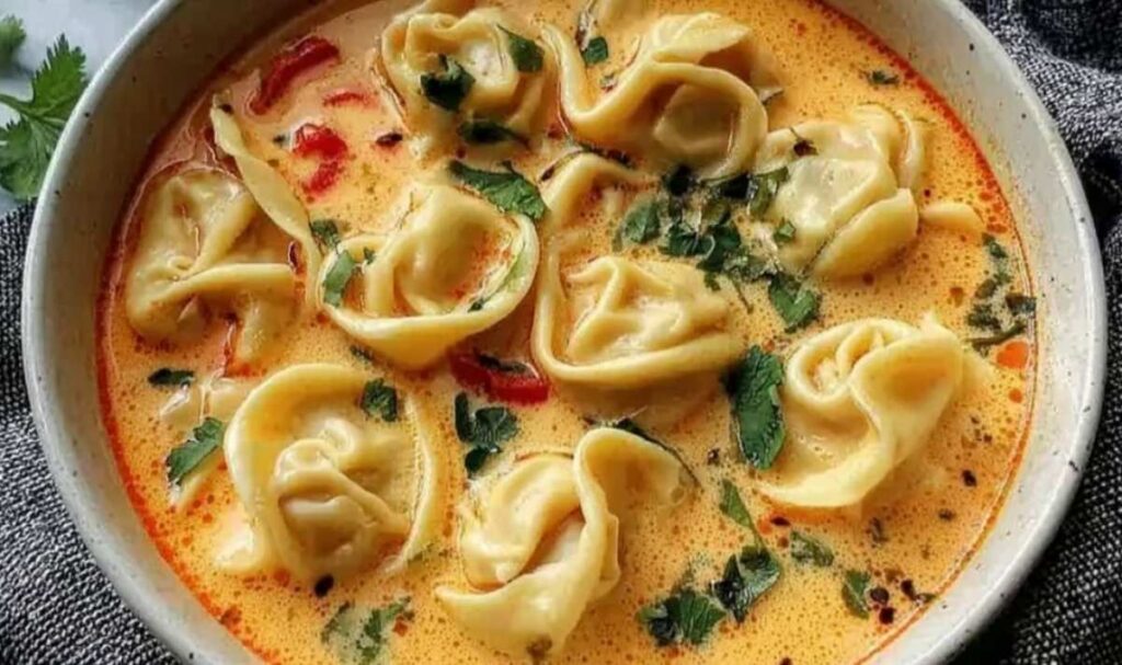 Cremige Thai-Knödel-Suppe 2 Cremige Thai-Knödel-Suppe in weißer Schüssel mit Koriander garniert und Limettenspalten