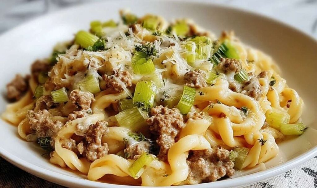 Cremige Käse-Lauch Pasta mit Hackfleisch serviert in weißem Teller mit geschmolzenem Käse