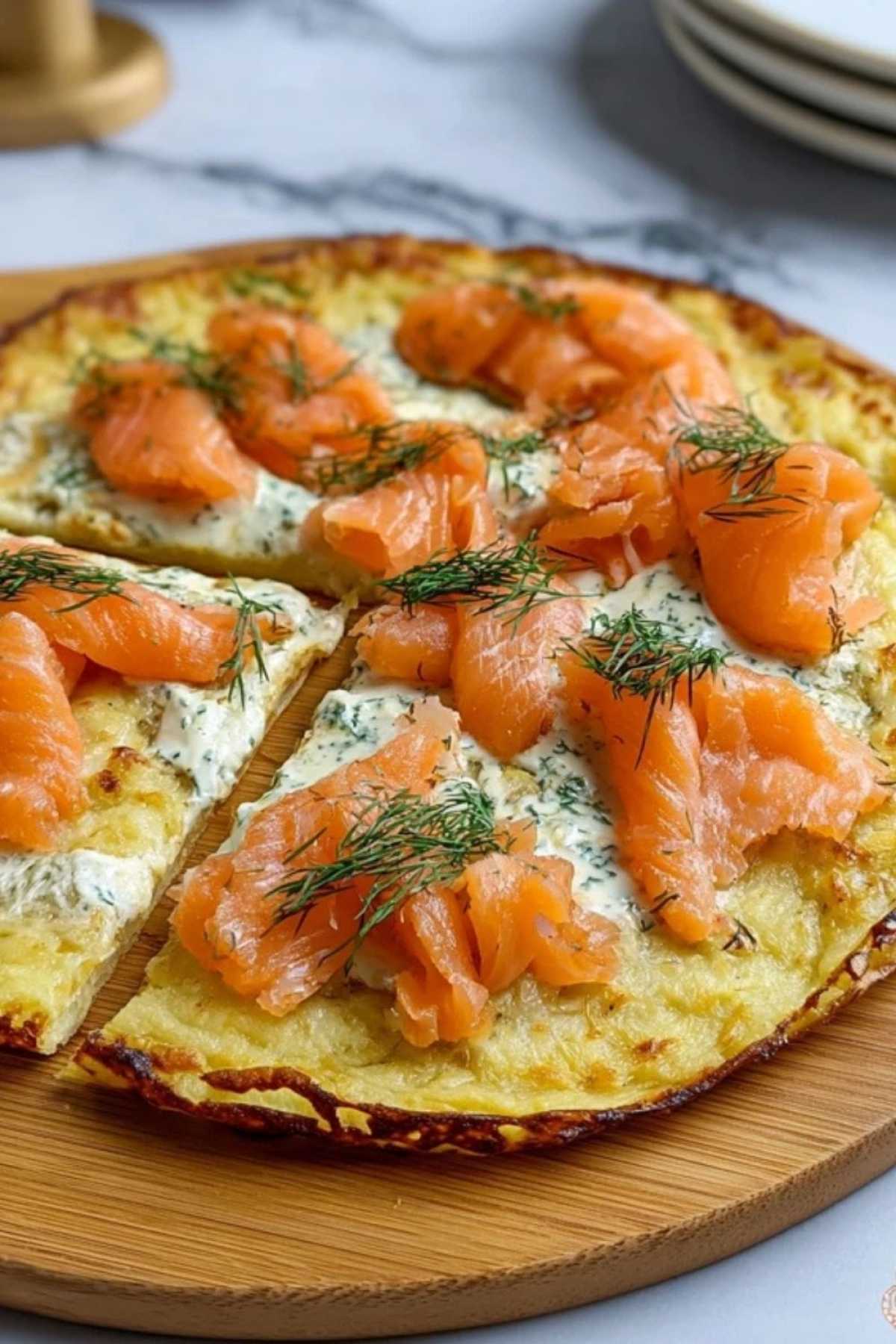Servierfertige Kartoffelpizza mit geräuchertem Lachs garniert mit frischem Dill