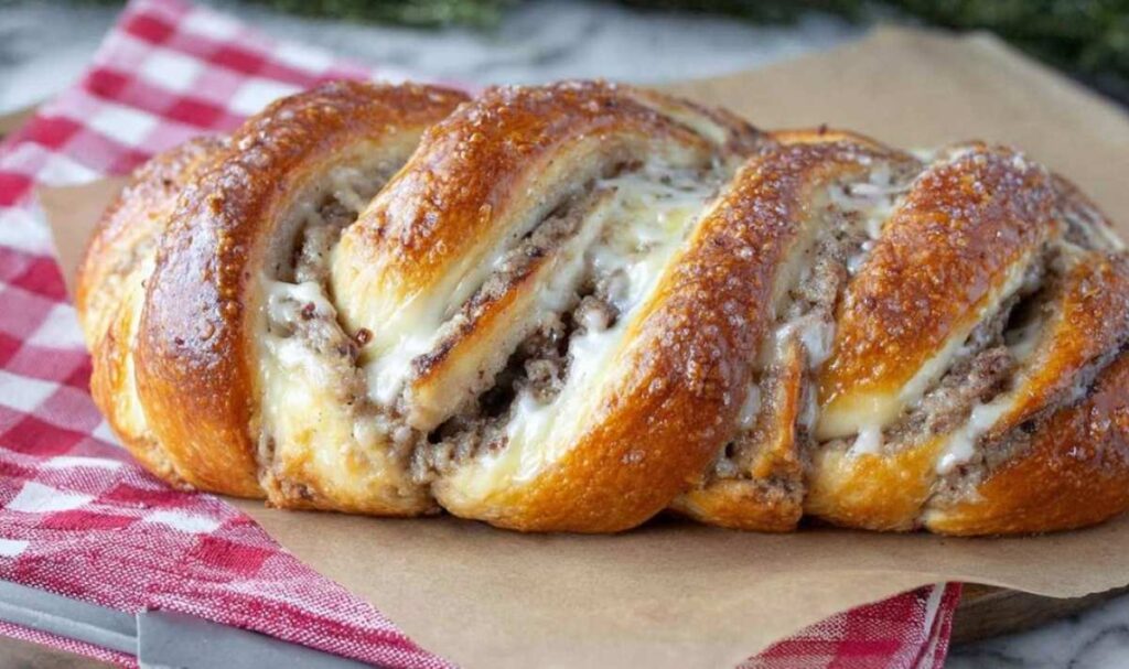 Goldbraun gebackener Nusszopf mit weißem Zuckerguss auf Backpapier