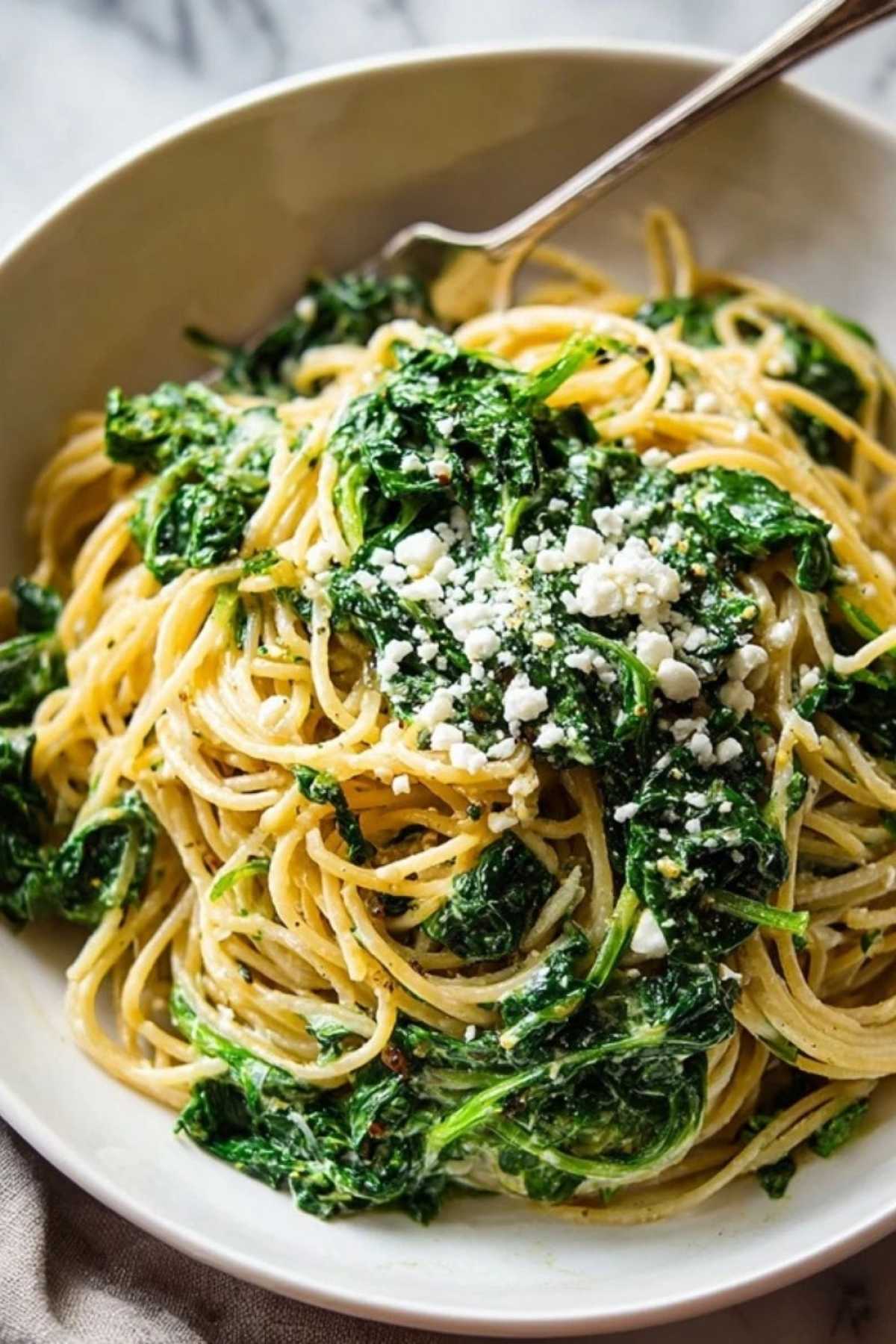 Nahaufnahme von Spaghetti mit Spinat Frischkäse-Sauce zeigt cremige Textur und frischen Spinat