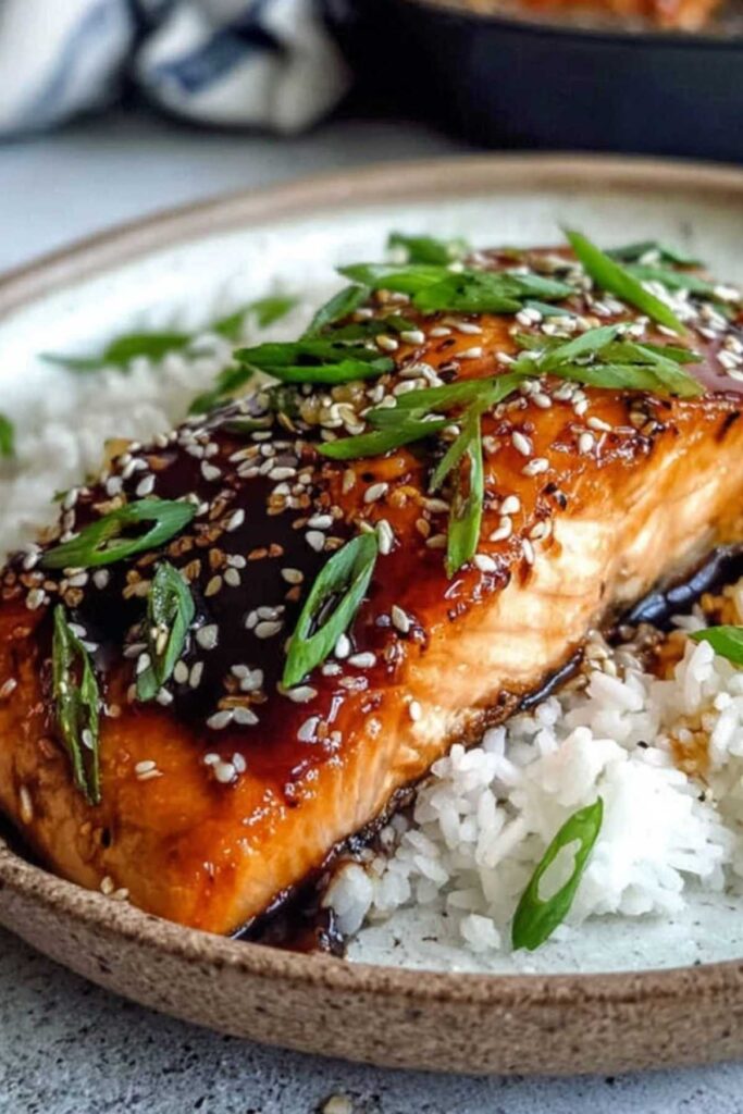 Teriyaki-glasierter Lachs brutzelt in der Pfanne mit karamellisierender Glasur