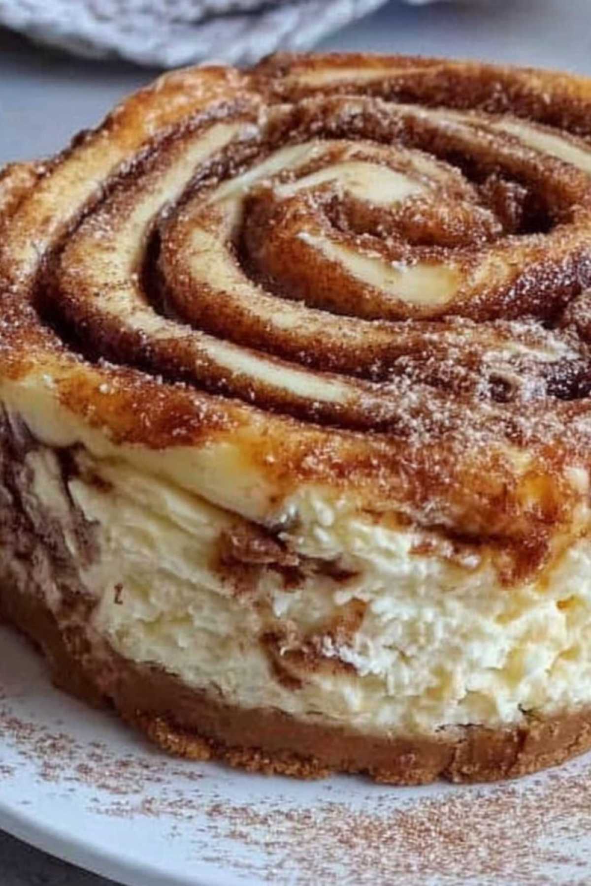 Zimtschnecken Käsekuchen mit Frischkäse und Zimt-Spirale auf weißem Teller