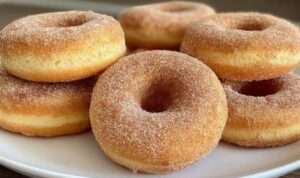 Frisch gebackene Airfryer Donuts mit einer dicken Schicht Zimt und Zucker auf einem weißen Teller Frisch gebackene Airfryer Donuts mit einer dicken Schicht Zimt und Zucker auf einem weißen Teller