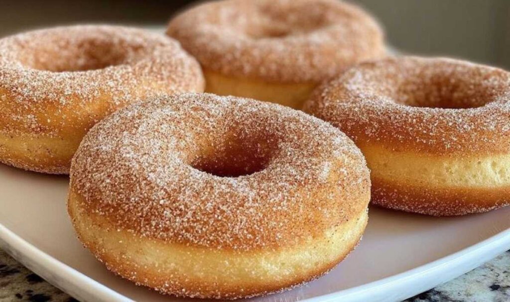 Frisch gebackene Airfryer Donuts mit einer dicken Schicht Zimt und Zucker auf einem weißen Teller